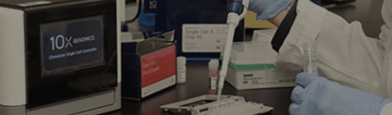 A gloved scientist uses a pipette at a laboratory bench, with various equipment and reagent boxes nearby, including a device labeled 10X Genomics.